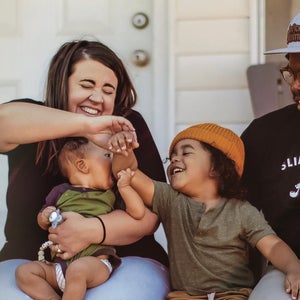 Family laughing with dog on porch