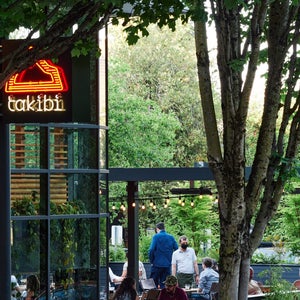 Exterior shot of Snow Peak's takibi restaurant with orange neon sign and trees