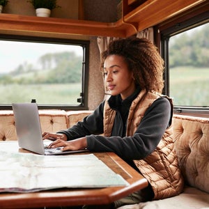 Woman using laptop in camper van on vacation