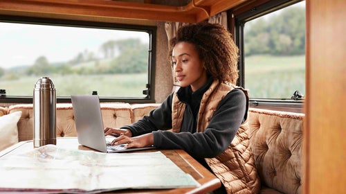 Woman using laptop in camper van on vacation
