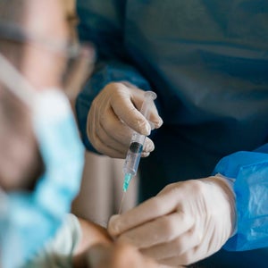 Doctor injecting covid-19 vaccine to senior man at his home.
