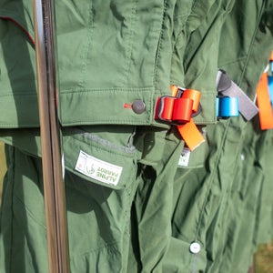 Green Alpine Parrot hiking pants hang on a clothing rack; plus-size outdoor apparel