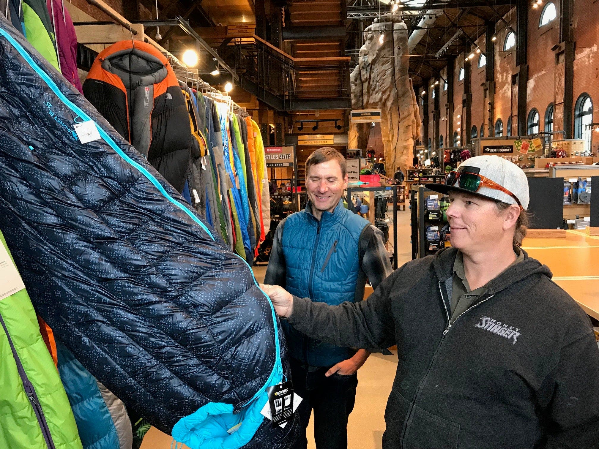 men looking at sleeping bags hanging up in store