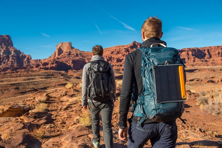 Two hikers in the desert with a BioLite Solar Panel strapped to one's backpack.