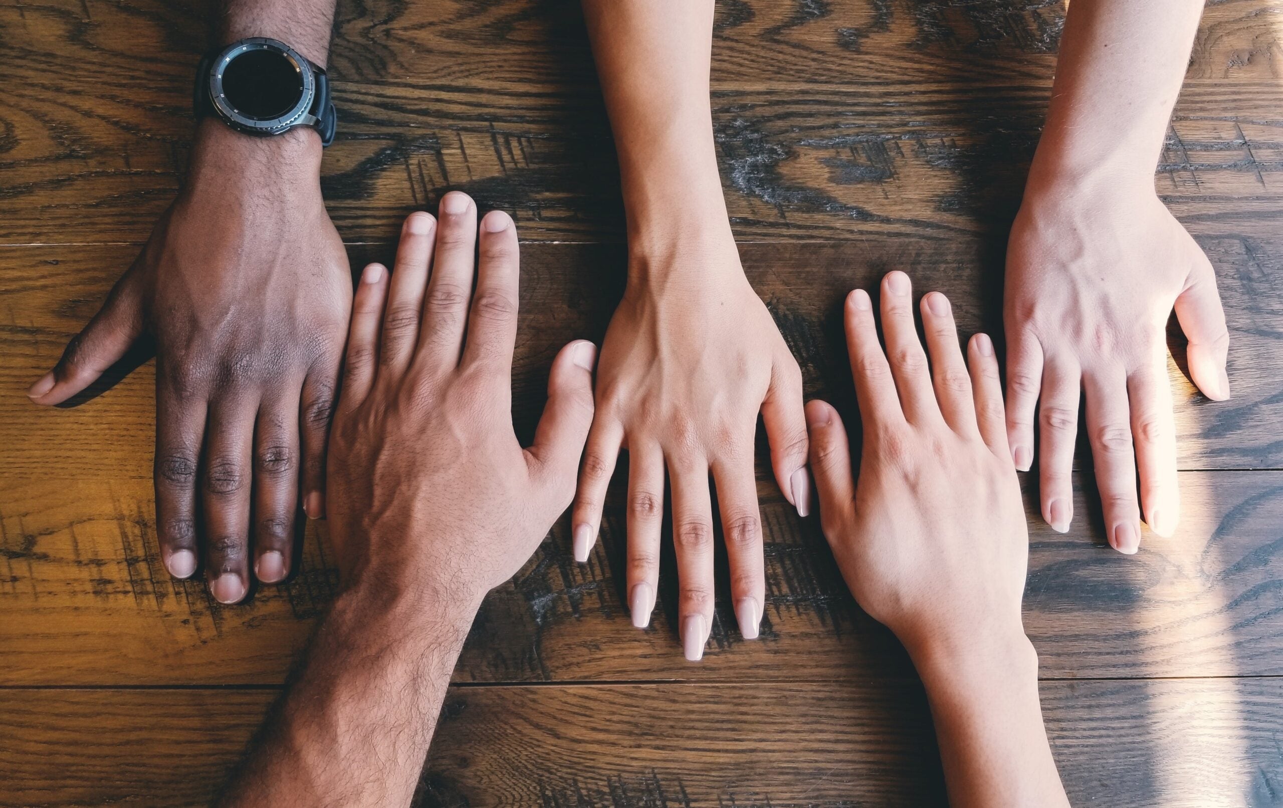 Five hands on a table