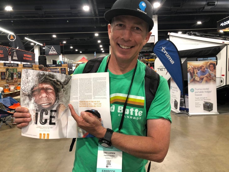 Man in green shirt and ballcap holding magazine | eric Larsen