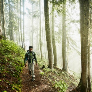 Man hiking along trial in forest on foggy morning