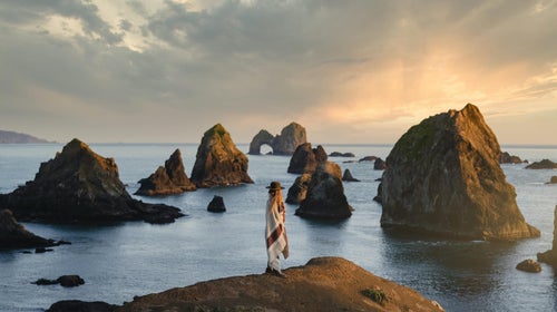 Woman standing in Ibex garment by the ocean