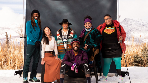 Six Black, Indiegenous, and people of color pose in front of a black backdrop