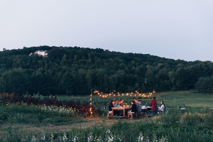 Friends have a dinner party in Maine under string lights