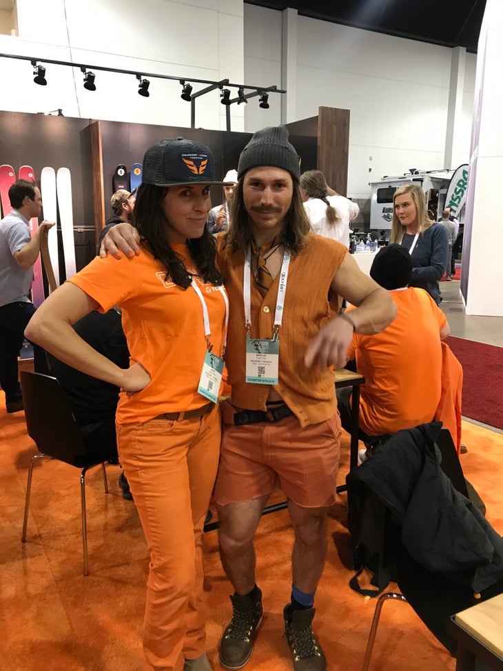 Maro LaBlance and man posing in a booth at Outdoor Retailer wearing orange.