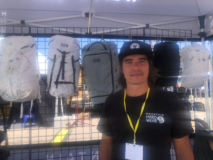 man in black t-shirt and ballcap stands in front of a wall of packs at Big Gear Show day 1