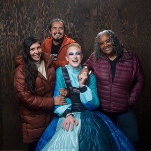 four people posing in front of brown background