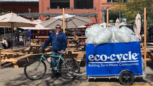 Man standing with bike bin full of plastic bags