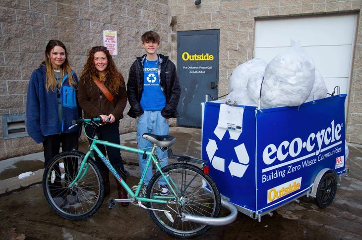 Three people standing with blue bike and blue Eco-Cycle trailer | polybag pilot