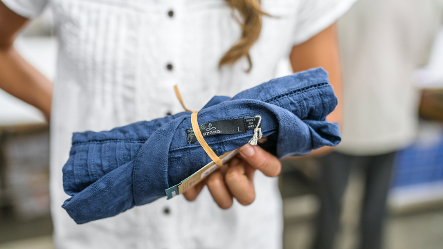 prAna's sustainable packaging: Blue denim prAna shirt rolled and tied with raffia