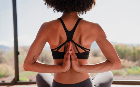 prana Black woman touches palms together behind her back