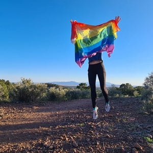 Woman holding a rainbow pride flag on a trail
