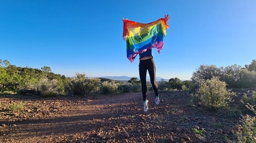 Woman holding a rainbow pride flag on a trail