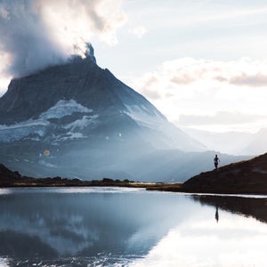 Silhouette of woman meeting beautiful sunset above mountain lake
