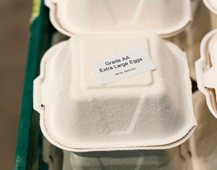 "White cartons with label that says Grade AA Extra Large eggs inside a green crate"