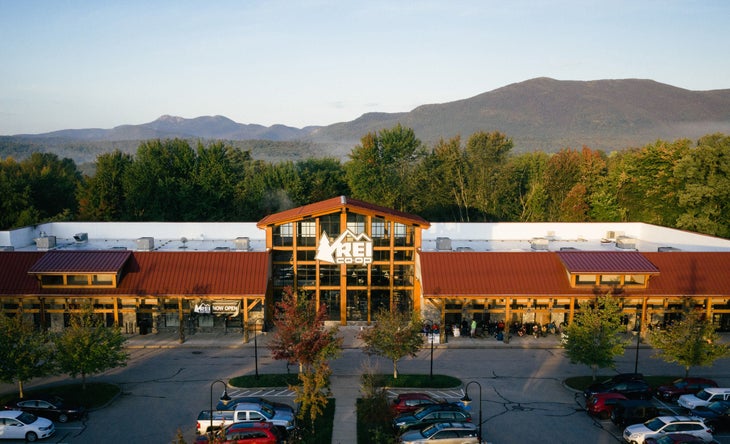 An REI store with trees and mountains in the background.