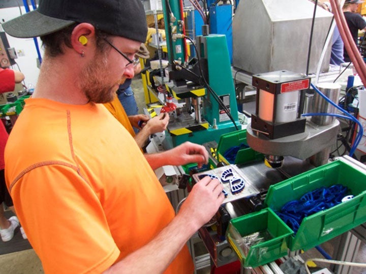 workerresize A worker in an orange T-shirt making a climbing cam at the Black Diamond facility in Salt Lake City, Utah