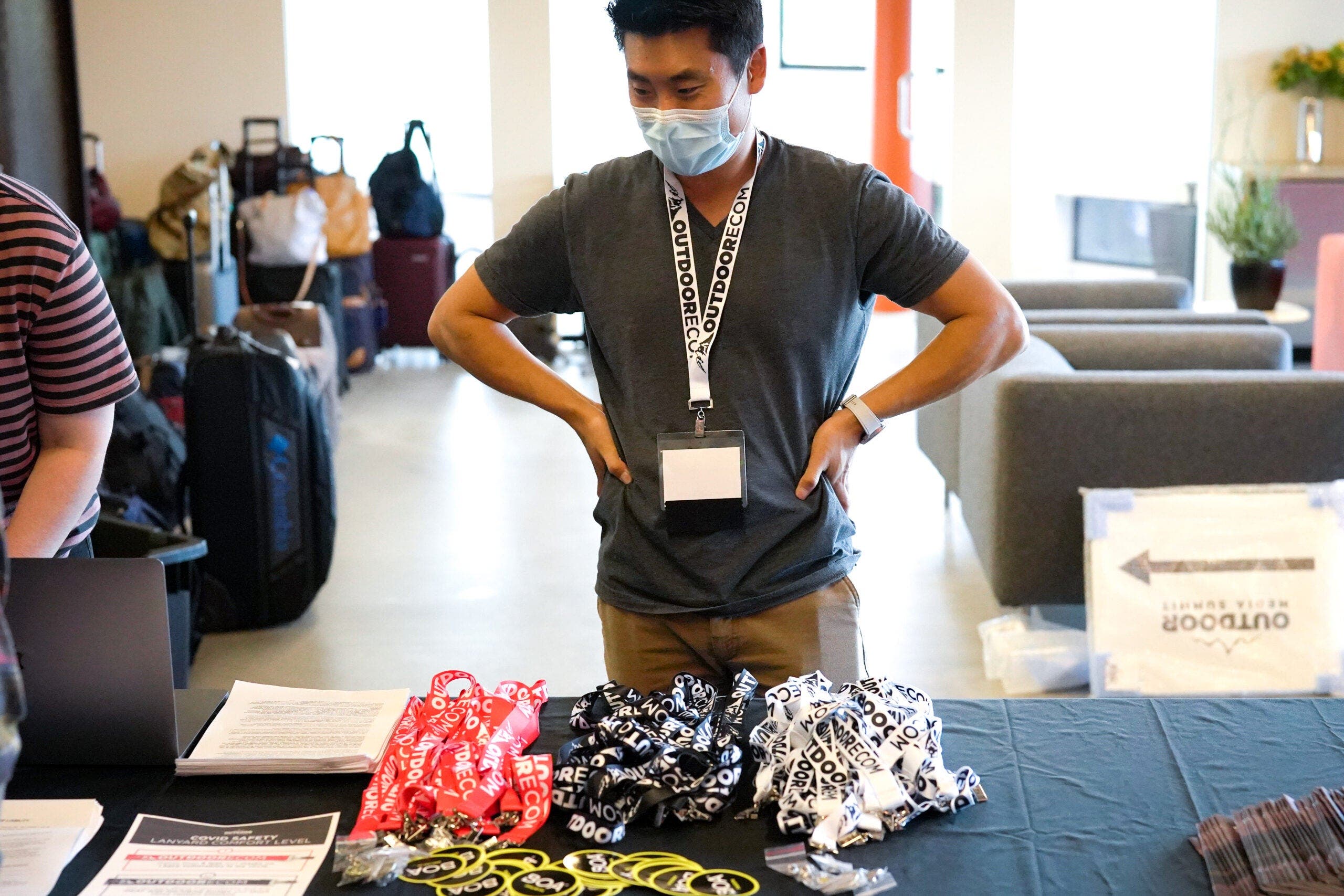 Yoon Kim stands at registration desk of Outdoor Media Summit with lanyards and stickers on the table