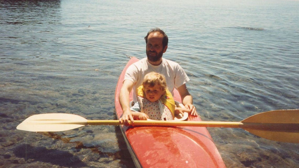 A father and son kayak together.