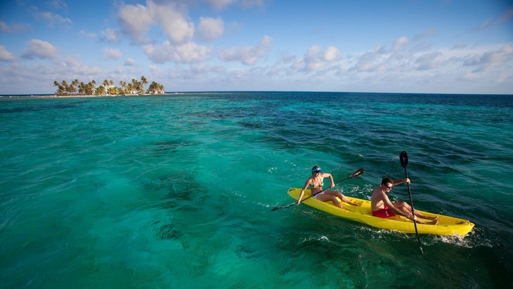 two people kayak off the coast of a tropical island in Belize