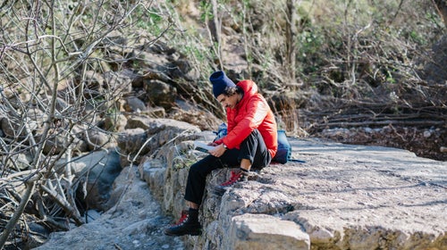 Young man sitting with book on the cliff. Horizontal outdoors shot.