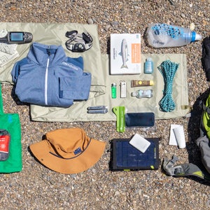 A collection of survival gear laid out on the ground for a bug-out bag