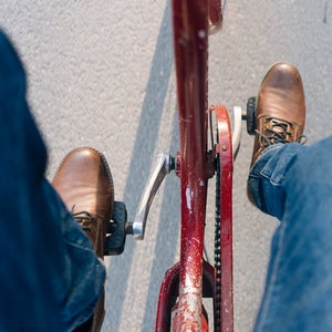 Man pedaling a bicycle in jeans.