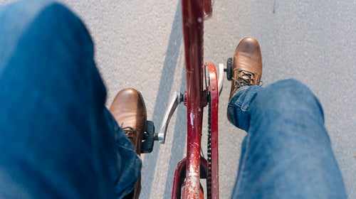 Man pedaling a bicycle in jeans.