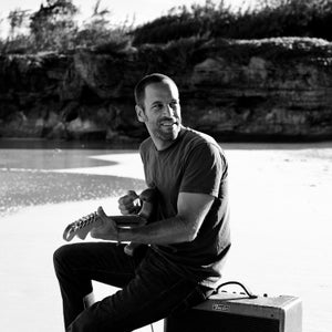 Jack Johnson plays an electric guitar on the beach