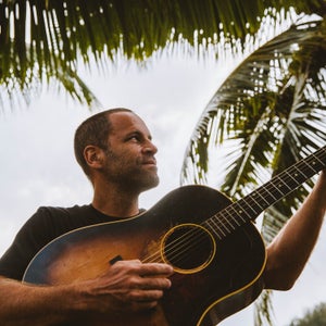 View from below of Jack Johnson playing an acoustic guitar outside