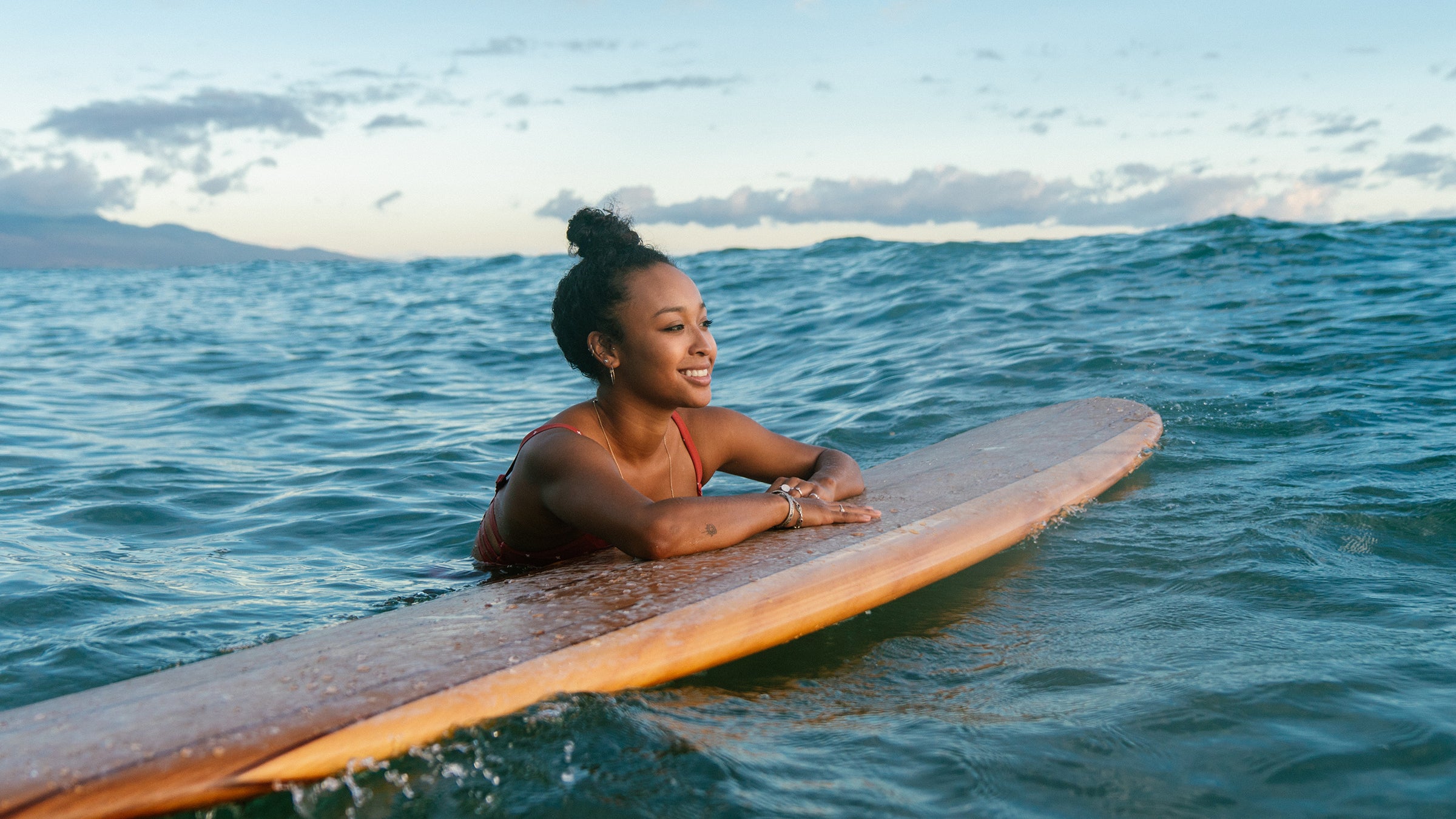 Young woman resting on her surfboard waiting for a wave. Hawaii 2019