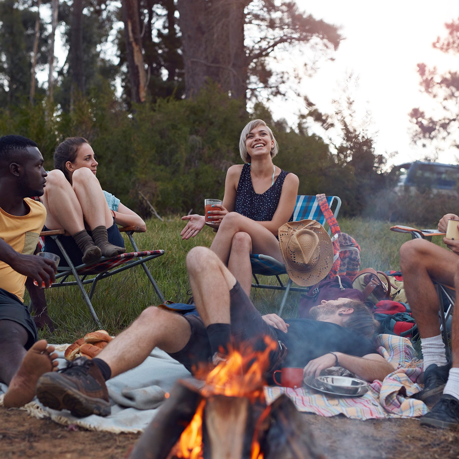 Group of friends on camping trip, by the lake with tent and making bonfire