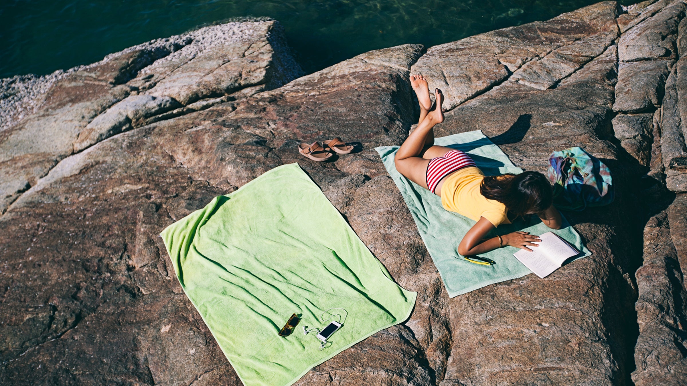 Woman lying on the beach and reading a book.