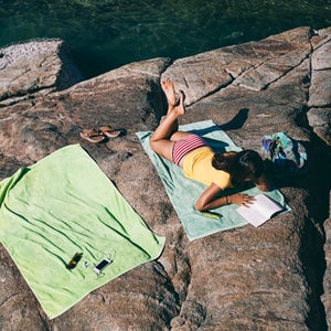 Woman lying on the beach and reading a book.