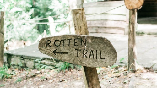 A wooden sign near a cabin reads 