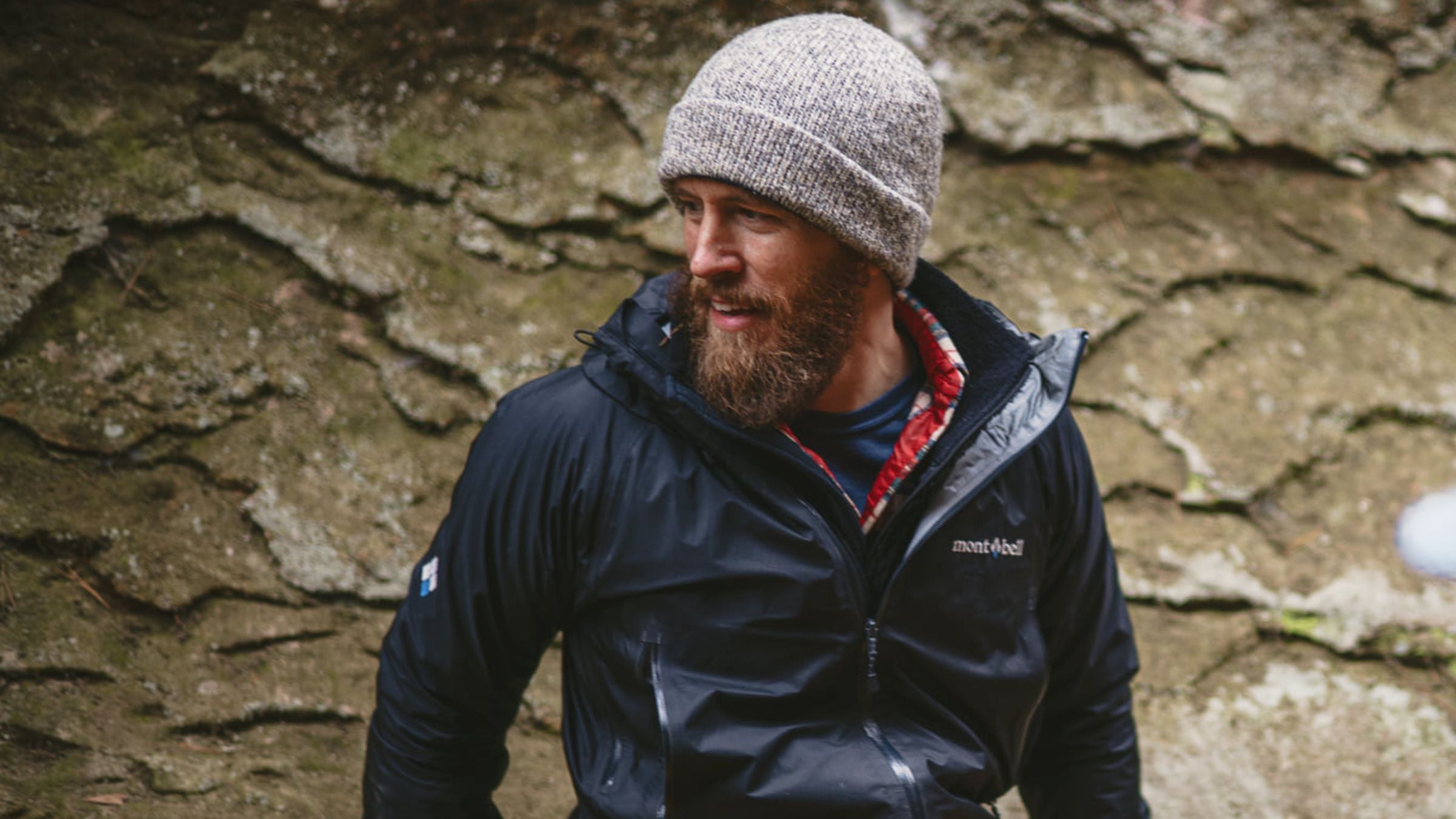 Man in beanie and jacket sitting on a rock