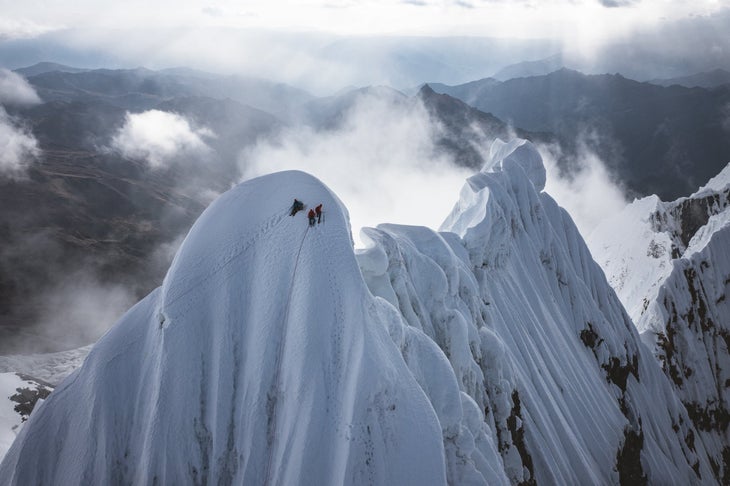 Three climbers on the snowy summit of Jirishanca, in Peru