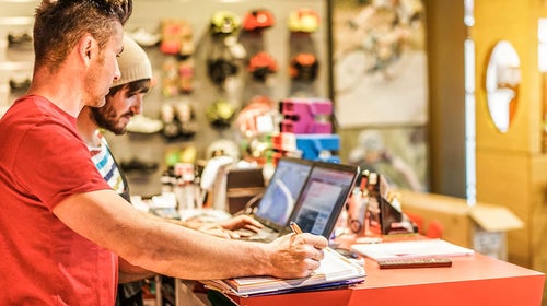 Man standing at cash register in outdoor retail shop