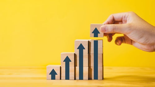 A hand stacking blocks with arrows on them