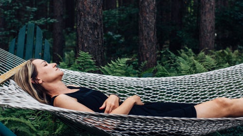 A woman listens to brown noise while napping in a hammock