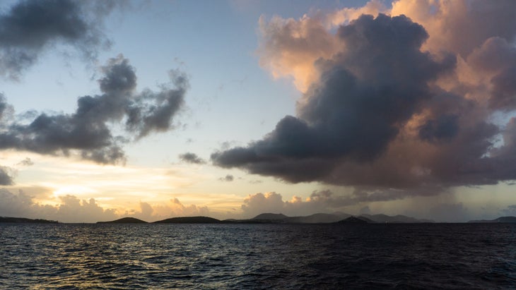 At sunset aboard a sailboat cruise, the Virgin Islands are cast in silhouette.
