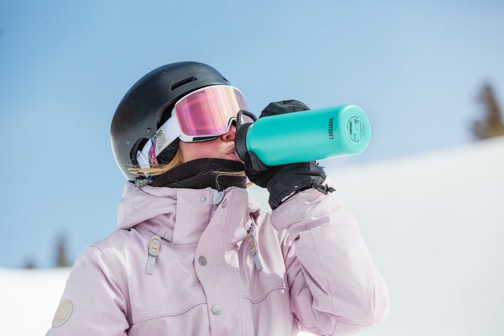 professional snowboarder drinking from a water bottle