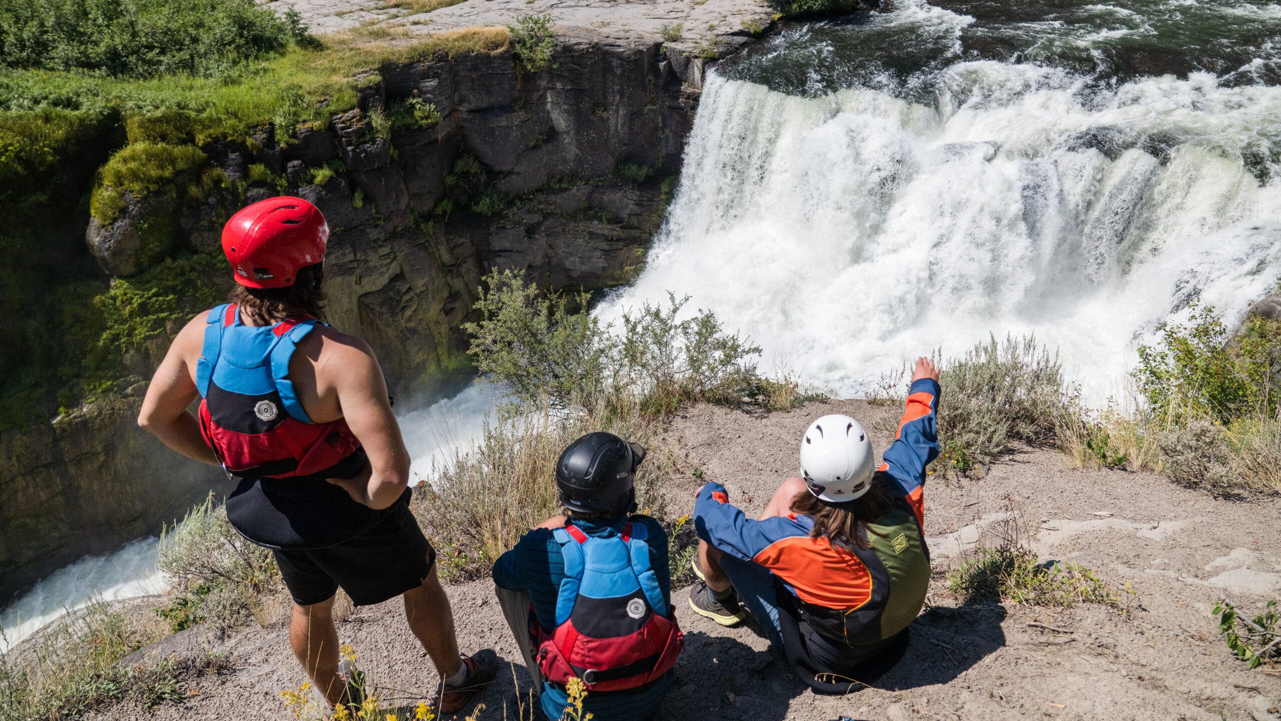 Kayakers look at a waterfall.