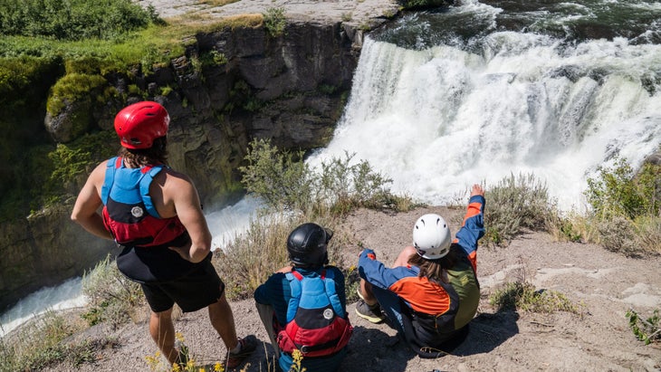 Kayakers look at a waterfall. 